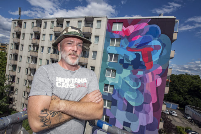 Künstler Stohead vor Fassadenkunstwerk