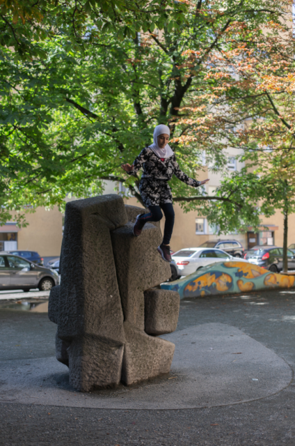 Mädchen springt von einer Skulptur